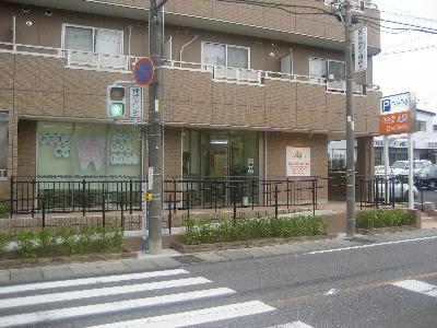 押しボタン式信号機の近くにあるおかまつ歯科の外観の写真
