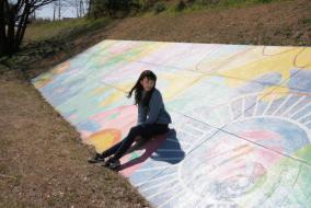 防波堤に制作されたコンクリート壁画の上に腰を下ろす女性の写真