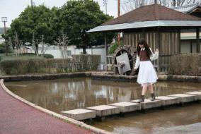 涼松せせらぎの道の水路に設置された石橋を渡る女性の写真
