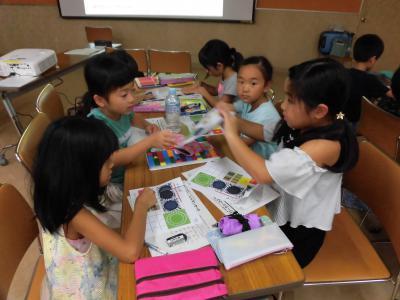 9月2日(日曜日)、町民会館で、親子参加型ワークショップ「発想力と決める力の育て方」が開催された際の各テーブルにて頭や手を動かし考える子どもたちの画像