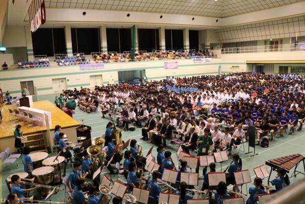 開会式にて大勢の出席者らの前で吹奏楽部が演奏している様子の写真
