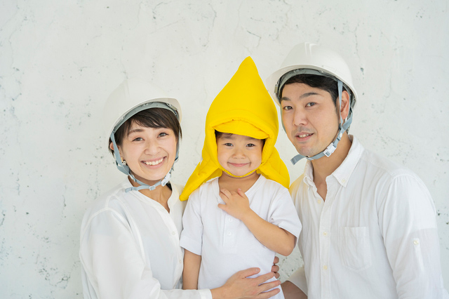 防護ヘルメットをかぶる夫婦と安全帽をかぶる子どもの画像