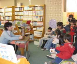 紙芝居で子供達に読み聞かせをしている写真