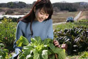 農場の畑で採れたての野菜を手にする女性の写真