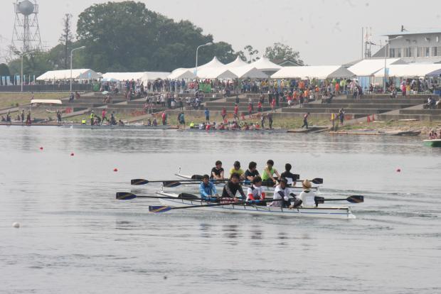 愛知池漕艇場で開催された第24回東郷町民レガッタの大会で試合をしているチームの奥に各チームのテントと選手たちの写真
