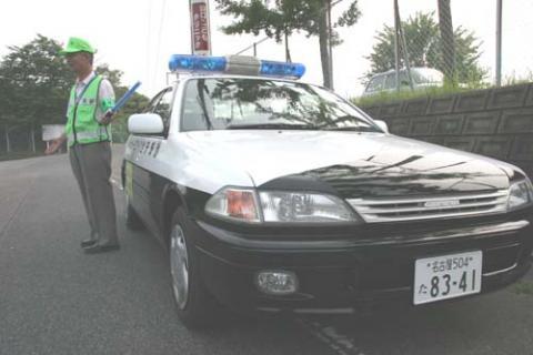 緑のゼッケンを着ている男性と青色パトロールカー